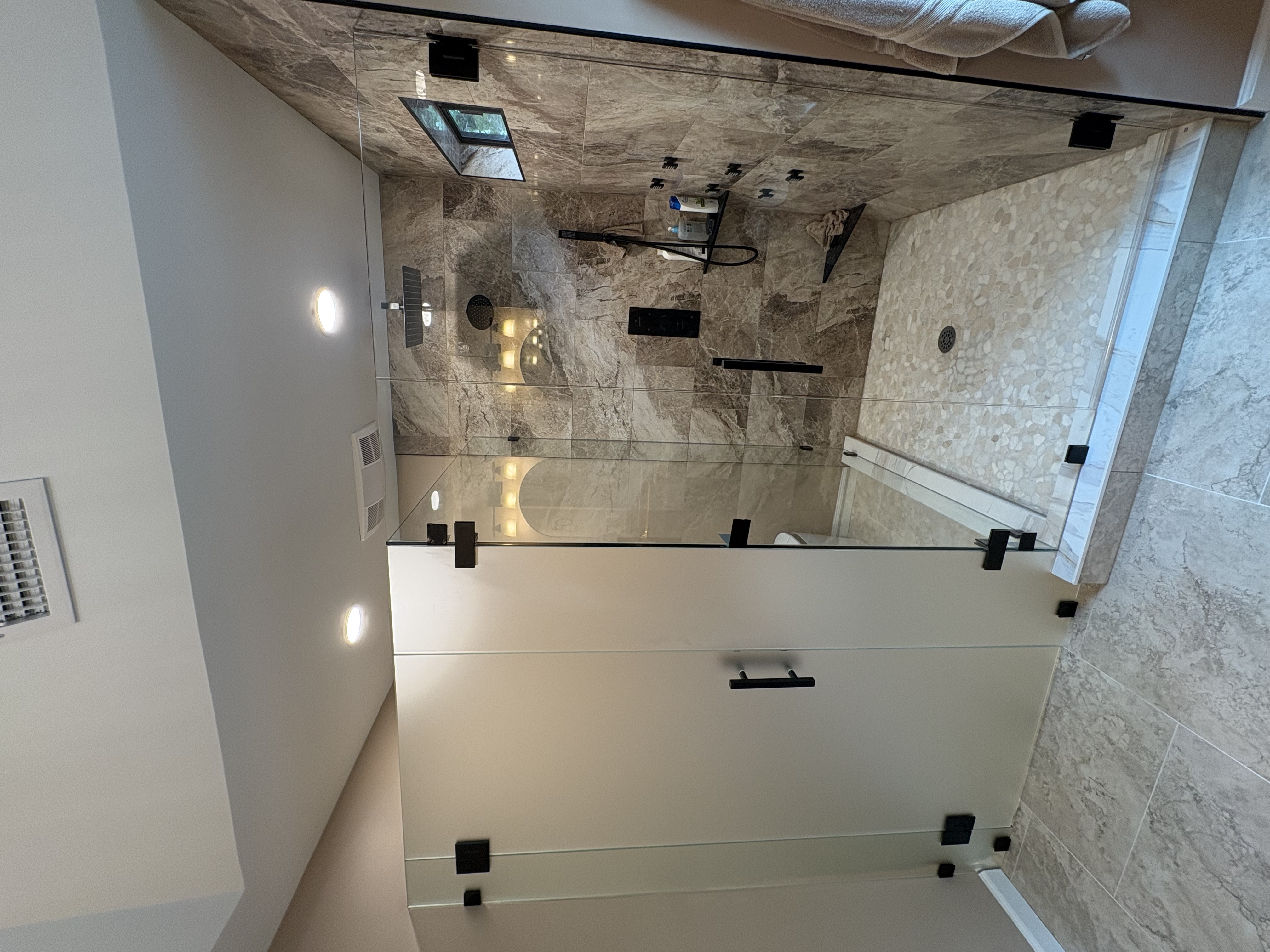 This is a toilet partition next to a shower enclosure to provide openness, privacy, and luxury!